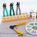 Jewelry-making tools including pliers and a stand on a table with beads and wire.