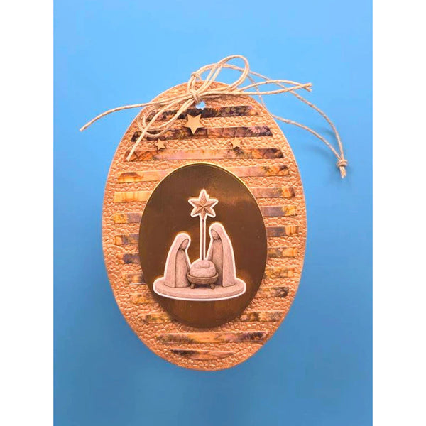 An oval Christmas ornament featuring a textured brown wood background with horizontal wood-grain stripes, a central metallic bronze oval containing a relief of the Holy Family and star, and a natural jute hanging string tied at the top.