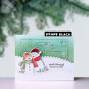 A handmade Christmas greeting card featuring two snowmen, one orange and one white, wearing red scarves and hats. The card has a green and white layered background with embossed snowflakes and the brand name 'Penny Black' visible on a sticker.