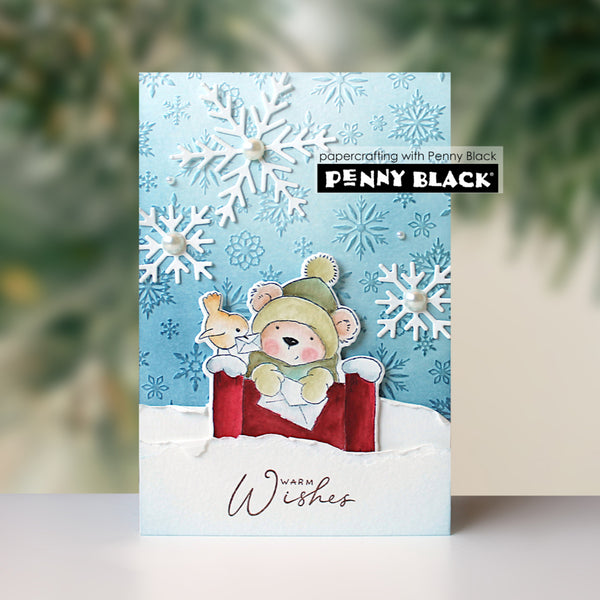 A handmade holiday greeting card featuring a cute bear and fox in a red sleigh against a light blue snowy background with white paper snowflakes. The card has 'Wishes' written at the bottom and a 'Penny Black' brand label on the front.