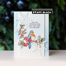 A handmade greeting card featuring a bluebird, red berries, and layered white snowflakes, with the text 'may this Christmas find your spirit light as a feather' and a Penny Black stamp brand label.