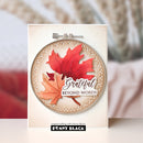 A handmade greeting card featuring a circular layered design with red and orange maple leaves, a beige scalloped border, and the words 'Grateful BEYOND WORDS.' The card is shown upright against a softly blurred warm-toned background, with the Penny Black branding visible at the bottom.
