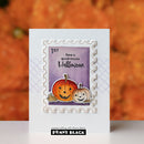 A handmade white greeting card featuring a die-cut stamp design with two carved pumpkins, a purple background, and the text 'have a spooky-tacular Halloween.' The card is photographed upright against a blurred orange autumn background, with a Penny Black brand label visible at the bottom.