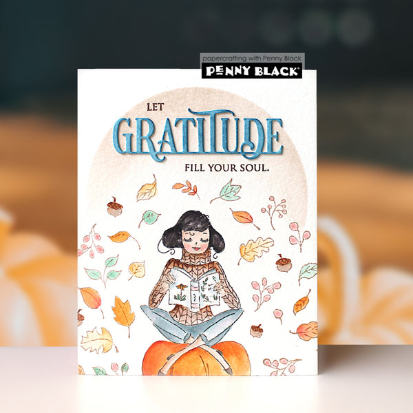 A vertical greeting card featuring a watercolor illustration of a girl reading on a pumpkin, surrounded by autumn leaves and acorns, with the text 'LET GRATITUDE FILL YOUR SOUL.' The card is branded with 'Penny Black' at the top, set against a blurred warm-toned background.