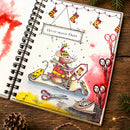 A spiral-bound notebook or journal page featuring a whimsical Christmas mouse illustration riding a sleigh, with stockings, scissors, and the text 'Christ-mouse Chaos' on a rustic wooden surface.