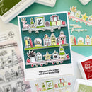 A handmade holiday-themed sticker card displayed on a mint green background with various crafting tools and stamps. The card features three illustrated shelves with Christmas decorations, houses, gifts, and stars, along with the stamped message 'Hope your holiday is filled with all your favorite things'.