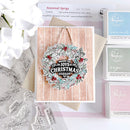 A handmade Christmas greeting card with a floral wreath design and the text 'MERRY JOYS OF CHRISTMAS season', styled on a kraft envelope with Ranger Fresh dye ink pads and clear stamp sheets on a white background.