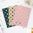 Three decorative laser-cut cards or paper sheets with star and moon patterns, displayed in dark green, glittery gold, and dusty pink on a white background with scattered paper confetti.