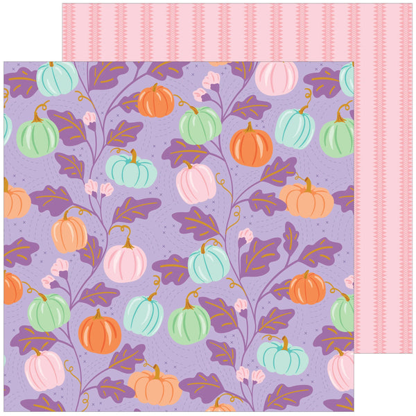 A square sheet of patterned paper with a lavender background and a repeating design of pumpkins in orange, mint green, and pale pink, with purple leaves and stems. A second pink striped paper sheet is partially visible behind it on the right side.