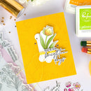 Yellow card with floral design and text, surrounded by crafting supplies on a light background