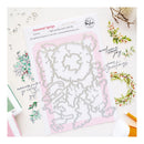 A flat-lay product photo of a Pincraft 'Seasonal Sprigs' 5-piece steel embosser die set. The silver metal dies are displayed on a pink backing card, surrounded by decorative stamped floral wreaths, a stamping tool, and a pencil on a white background.