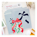 A set of layered acrylic stencils for crafting, featuring a large dark navy bow and a red mistletoe with green leaves and small pink berries, displayed on a light-colored flat-lay surface with craft tools and a card.