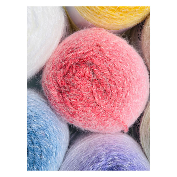 A close-up of fluffy yarn balls in soft pastel and bright colors, with a pink ball centered and other visible balls in white, yellow, blue, and lavender.