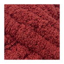 A close-up of a textured, chunky knit fabric in a warm rust red color, framed by white borders on the left and right sides.