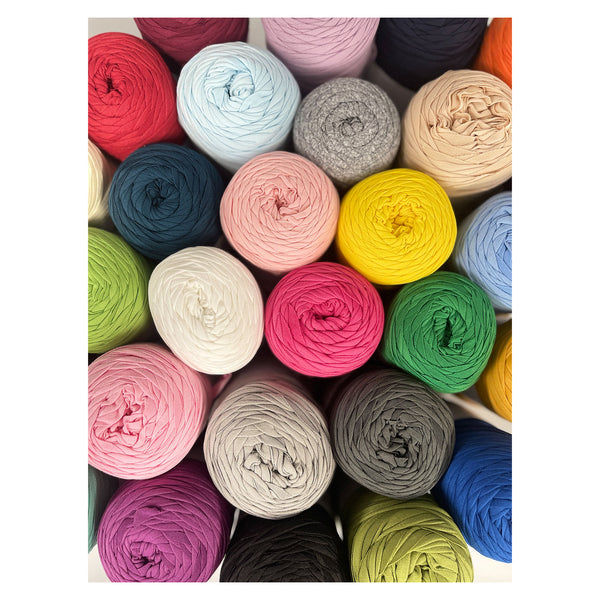 A top-down view of multiple skeins of yarn in assorted colors, including red, pink, blue, green, yellow, gray, beige, purple, and black, arranged closely together.