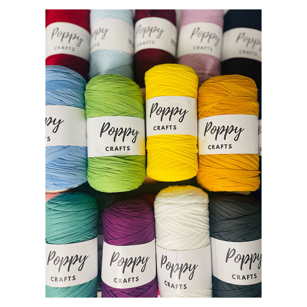 Nine skeins of Poppy Crafts yarn arranged in a grid, showing a variety of colors including red, light blue, green, yellow, orange, teal, purple, white, and gray. Each skein has a white paper label wrapped around it with the brand name 'Poppy Crafts' printed on it.