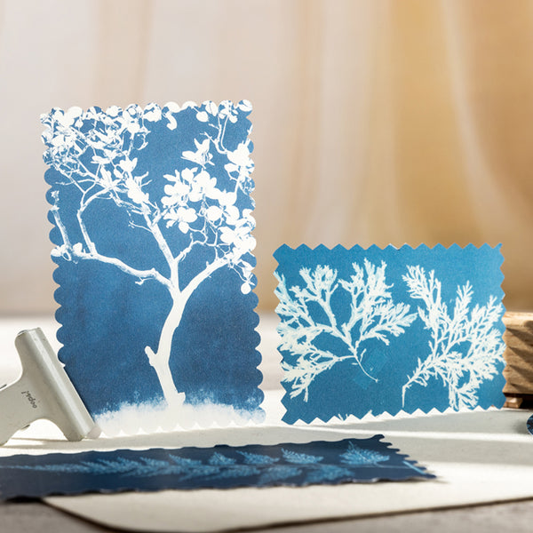 Two blue stencils with white tree and leaf designs on a light background