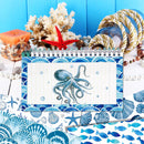 A spiral-bound notebook with a blue octopus illustration on the cover, styled with nautical props including a red starfish, coral, rope, shells, and a blue wooden background.