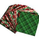 A fan of patterned paper napkins or table linens on a white background, with a prominent green plaid napkin in front and multiple red, green, black, and white holiday-style plaid patterns layered behind it.