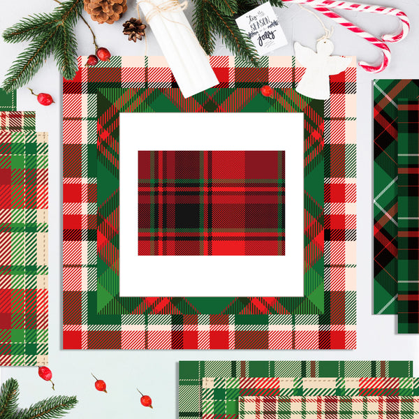 A styled flat-lay of Christmas-themed plaid paper sheets and cardstock designs, featuring red, green, and black tartan patterns with holiday decorations like pine branches, candy canes, and ornaments on a white background.