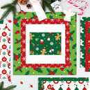 A styled flat-lay of Christmas-themed paper cardstock and patterned paper sheets. The main sheet features a green background with holly and snowflake patterns, surrounded by a red border, with a central patterned insert showing gingerbread men, stockings, and candy canes.