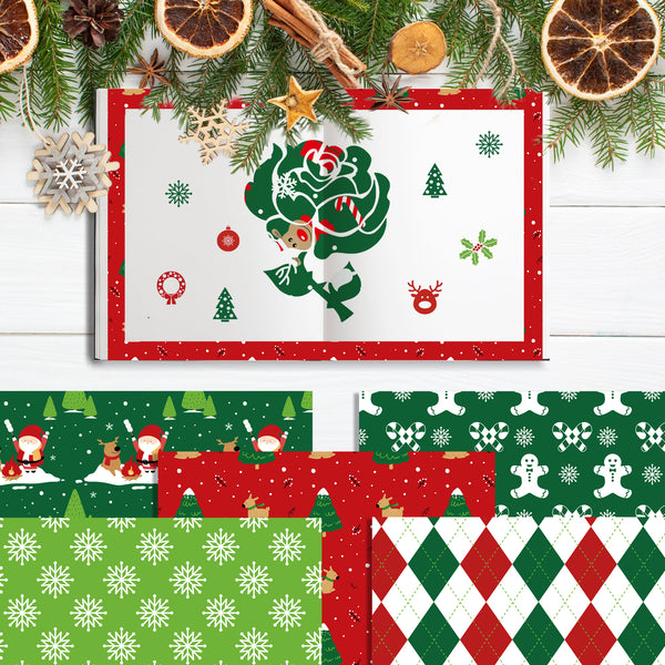 A Christmas-themed paper craft kit or scrapbook paper set displayed on a white wood background with holiday decorations. The main open booklet shows a green tree with a Santa Claus figure inside, surrounded by red and green festive patterns.