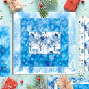 A flat-lay display of blue winter-themed scrapbooking papers with snowflakes, trees, and snowy pine trees, styled with Christmas gifts, evergreen branches, and red berries on a light blue background.