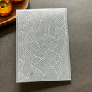A rectangular translucent silicone mold with an embossed geometric interlaced pattern, shown on a gray textured surface with a small decorative pumpkin in the corner.