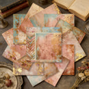 Collection of vintage-style stationery items on a textured surface with books and dried flowers.