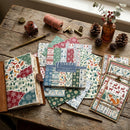 Collection of patterned paper sheets and stationery items on a wooden table.