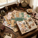 A styled flat-lay of Biscuit Paper Co's Christmas Gingerbread-themed paper sheets and scrapbook papers arranged on a rustic wooden table with vintage props including an alarm clock, scissors, and a small window.