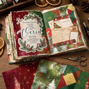 Open book with Christmas-themed paper designs and text on a wooden surface.