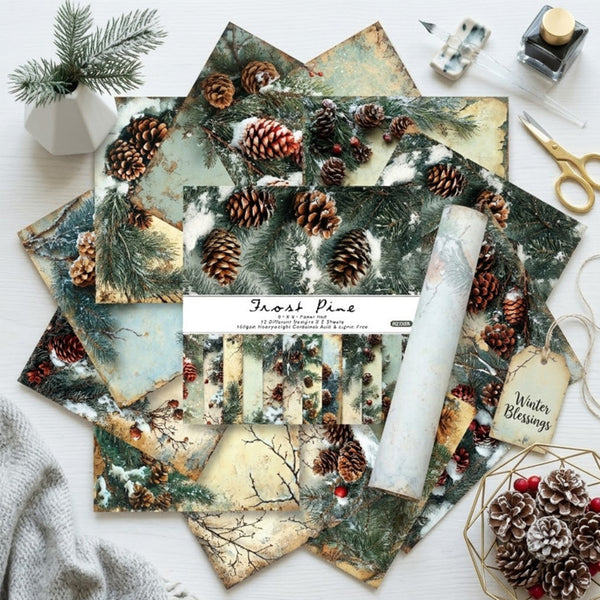 A flat lay of printed scrapbook paper sheets and a matching paper roll featuring a winter forest theme with pinecones, evergreen branches, snow, and rustic beige tones. The package label reads 'Forest Pine' and includes a small hanging tag that says 'Winter Blessings.