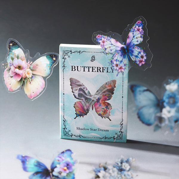A boxed butterfly-themed product labeled 'BUTTERFLY' and 'Shadow Star Dream' stands upright on a reflective surface, surrounded by translucent butterfly decorations in pastel blue, pink, purple, and teal.