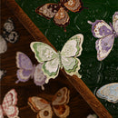 Decorative paper butterflies on a wooden surface with a green textured background