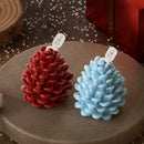 Two pinecone-shaped candles, one red and one light blue, displayed on a round brown tray with a holiday-themed background.