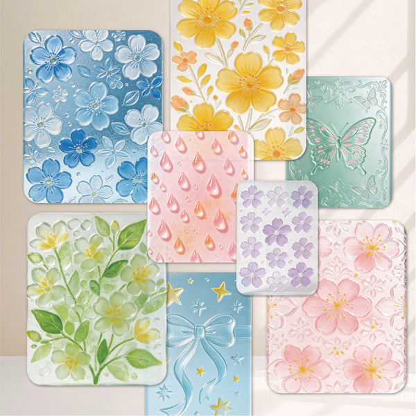 A set of decorative rectangular cards or tiles with rounded corners, each featuring a different pastel floral and abstract pattern. The designs include blue flowers, yellow flowers, a butterfly, raindrops, green leaves, a blue bow, purple flowers, and pink cherry blossoms, arranged on a light beige background.