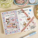 Open book with cat-themed pages on a textured surface with yarn and crochet items.