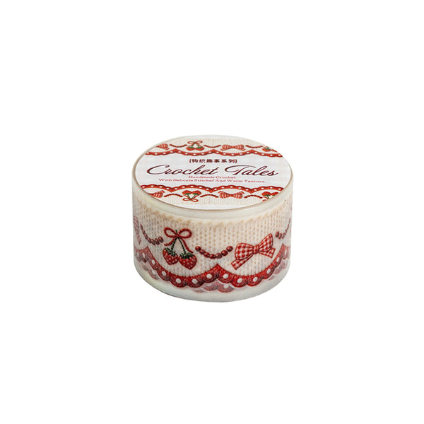 A round roll of 'Crochet Tales' washi tape with a white background, featuring red lace borders, bows, and cherries, shown on a plain white background.
