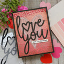 Card with 'love you' text on a wooden surface with decorative elements