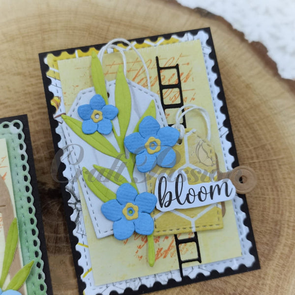 Handmade card with blue flowers and 'bloom' text on a wooden surface
