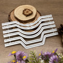 Set of white metal wavy rulers on a wooden surface with flowers in the foreground