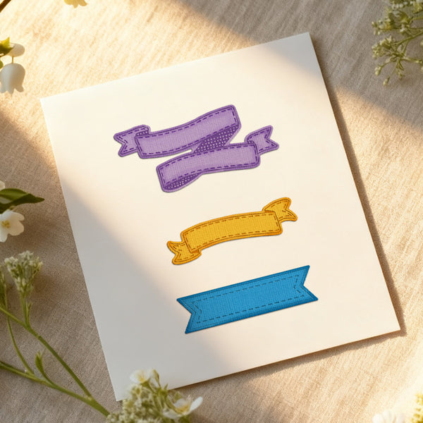 Three colorful fabric banners on a white card with flowers around