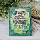 Decorative card with motivational quote on a wooden surface with plants and jewelry in the background