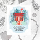 A decorative card or craft design featuring a small house with a red roof, teal scrollwork, mint clouds, and a heart on a pale blue shield shape, with the quote 'MAY YOUR WALLS KNOW JOY.