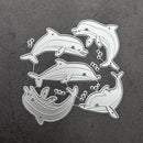 A set of five silver metal dolphin-shaped craft dies arranged on a dark textured gray background.