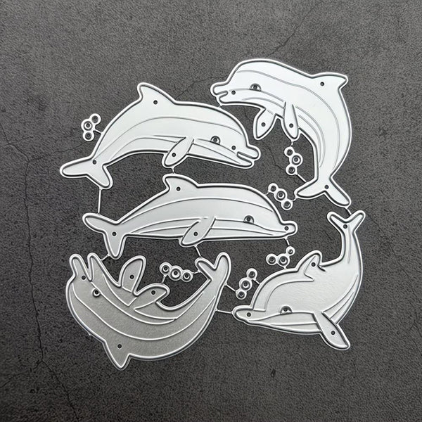 A set of five silver metal dolphin-shaped craft dies arranged on a dark textured gray background.