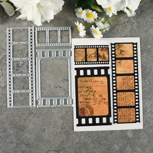 A flat-lay of a metal embosser or stamping template shaped like vintage film reels, shown next to a sample stamped card featuring black film borders and warm tan handwritten script details on a white background, styled with white flowers on a gray textured surface.