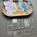 A set of metal die-cut stamping templates arranged on a gray surface, with two wooden trays holding matching decorative paper sheets above them.