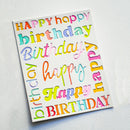 A square white card featuring colorful, playful typography with the words 'Happy Birthday' repeated in multiple pastel and bright gradient lettering, photographed on a light textured background.